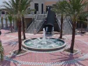 A fountain in the middle of a courtyard with palm trees.